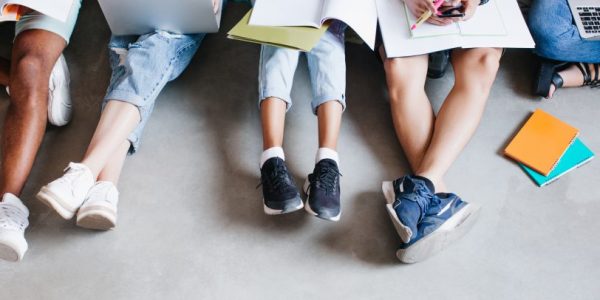overhead-portrait-of-young-people-with-laptops-and-smartphones-sitting-together-on-the-floor-students-writing-lectures-holding-textbooks-on-their-knees-1170x406